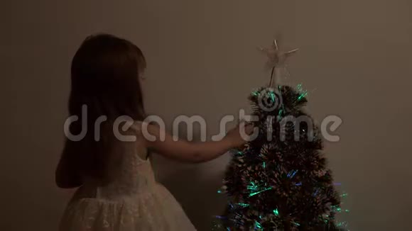 快乐的小女孩在圣诞树旁玩耍儿童和成人假期新年圣诞树快乐视频的预览图