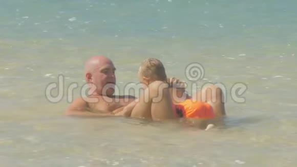 孩子和爸爸在热带度假胜地的清澈海水中玩得开心视频的预览图