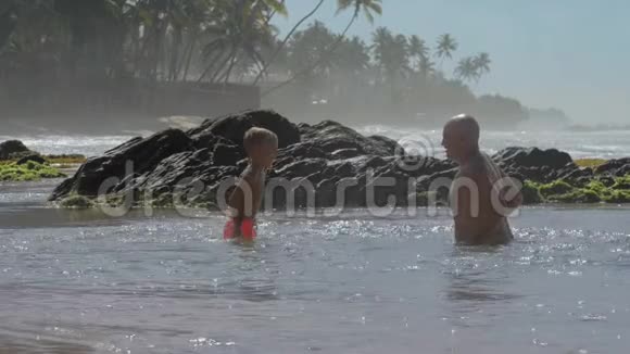 爸爸和男孩在宁静的海洋中尽情地泼水视频的预览图