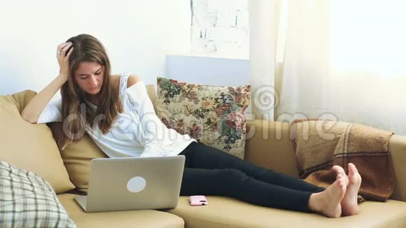 沙发上用笔记本电脑的年轻女子视频的预览图