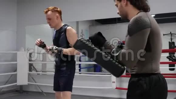 拳击手在教练手中踢手套他在环边有一个个人训练视频的预览图