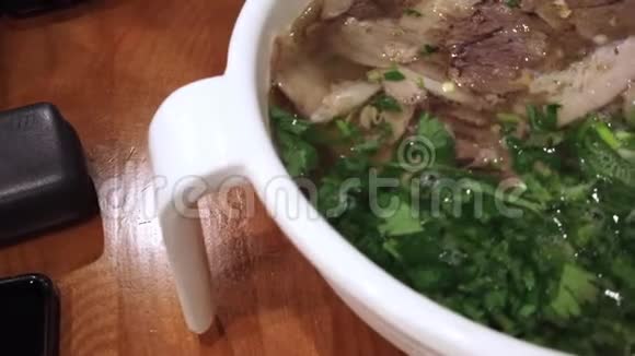 鲜切的香牛肉和汤中切碎的香菜视频的预览图