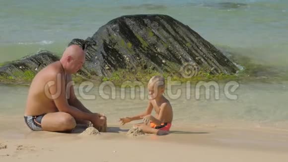 爸爸在沙滩上和一个可爱的儿子玩耍视频的预览图