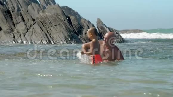 阳光明媚的一天爸爸和儿子一家人在海洋湾休息视频的预览图