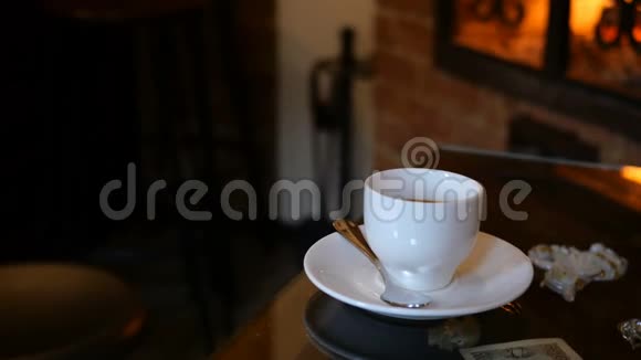 咖啡杯放在有壁炉的咖啡厅或餐厅的桌子上桌上闪着火焰浪漫的环境视频的预览图