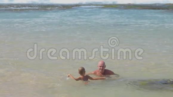 男孩和父亲一家人在平静的海湾游泳视频的预览图