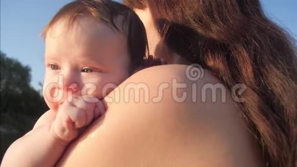 一个年轻的妈妈抱着一个正在吸拳头的小婴儿对幼儿的教育妈妈照顾孩子这就是视频的预览图