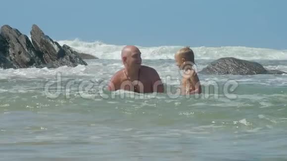 父亲教小儿子在老岩石附近的海里潜水视频的预览图