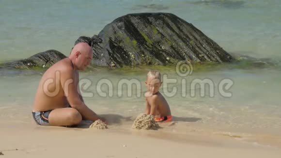 爸爸和可爱的男孩在冲浪线上玩湿沙视频的预览图