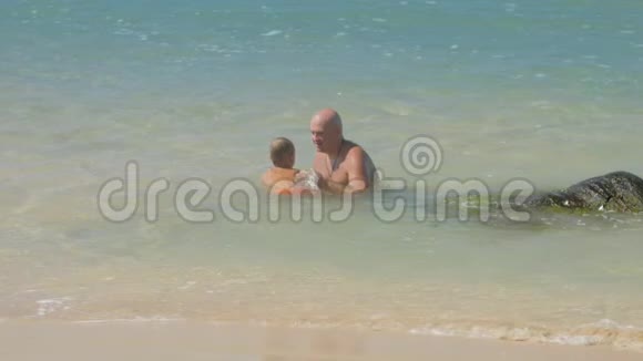 爸爸和小儿子在晴天在蔚蓝的海洋里游泳视频的预览图
