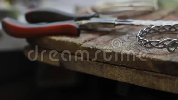 在珠宝商桌面上特写一个成品银手镯手工制作银珠宝选择性聚焦视频的预览图