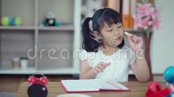 小女孩吃饼干写在书上视频的预览图