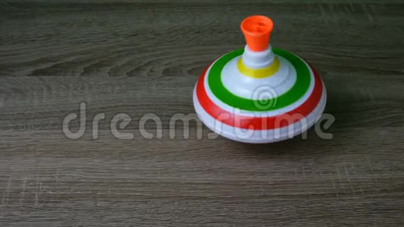 多色塑料纺顶或旋转陀螺是学龄前儿童的传统玩具在木头上旋转成圈视频的预览图
