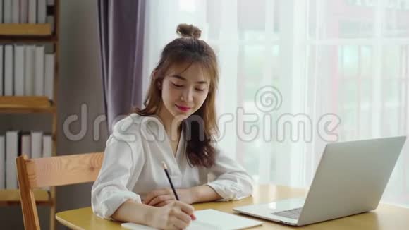 年轻作家女用铅笔在笔记本上写字视频的预览图