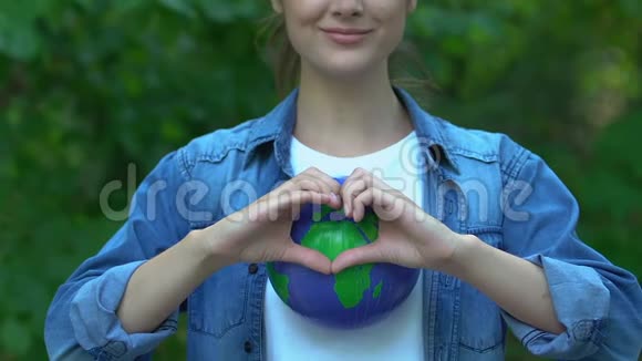 在地球仪地球护理环境意识上展示心脏姿势的女人视频的预览图
