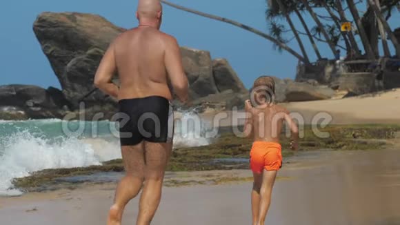 男孩和爸爸一起在美丽的海滩上跑步视频的预览图