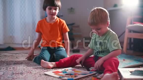 两个兄弟坐在地板上在家玩婴儿牌视频的预览图