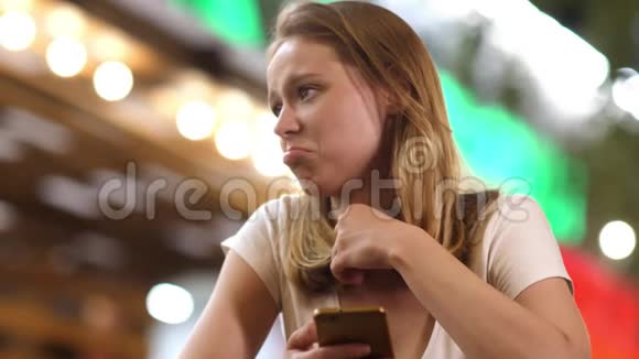 失望的女孩晚上在咖啡馆里用手机视频的预览图