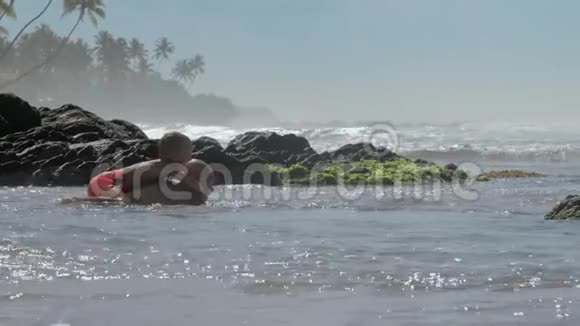 父亲和一个可爱的男孩在大海里的石头上游泳视频的预览图
