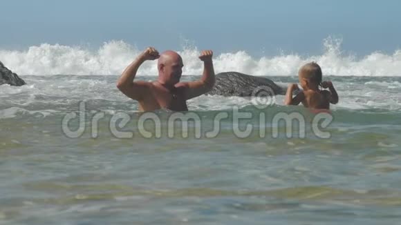 父亲和小孩在温暖的海洋中展示肌肉视频的预览图