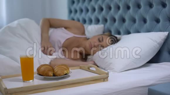 女孩睡在酒店房间在靠近床的托盘上准备早餐五星级服务视频的预览图