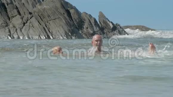 快乐的爸爸在阳光明媚的日子里教孩子在老悬崖附近游泳视频的预览图
