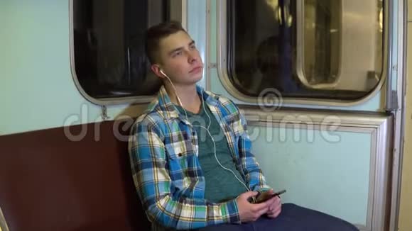 一个年轻人在地铁列车上用耳机听音乐旧地铁车视频的预览图