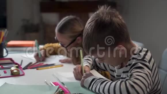 微笑的白种人男孩在练习本中写作和交谈的肖像戴眼镜的女孩嘲笑背景视频的预览图