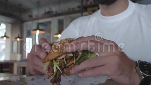 特写多汁的汉堡一个人手里拿着一只鸭子然后一个人咬一个汉堡吃汉堡的人4k4k录像60英尺视频的预览图