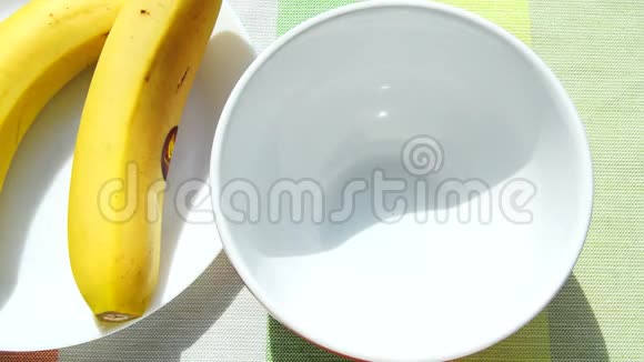 甜巧克力薄片倒入一个白色的碗里作为一份营养早餐盘子旁边是香蕉阳光在摩尔视频的预览图
