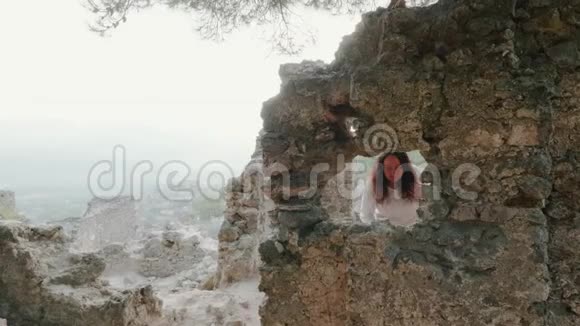 旅行的女人透过窗户从雾蒙蒙的高地上被毁的建筑看着镜头一位游客走进来视频的预览图