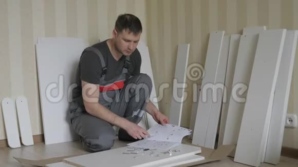 男工装配家具在家阅读说明和检查细节视频的预览图