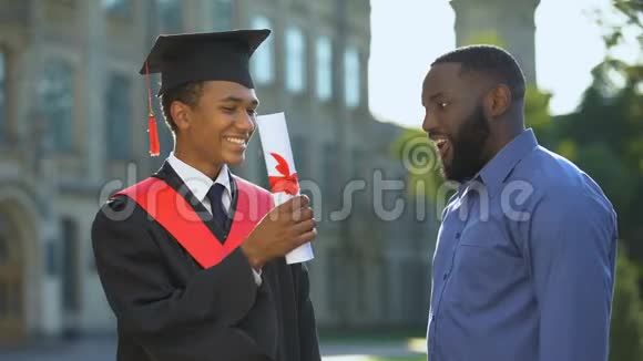爸爸感到自豪的十几岁的儿子拿着大学文凭毕业成功视频的预览图
