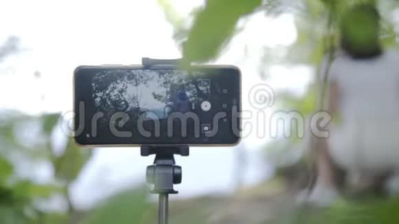 在山上的户外森林里为自己拍照设置数码相机的女人视频的预览图