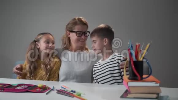 快乐的白人女人和她聪明的孩子坐在桌子旁美丽的年轻母亲拥抱女儿视频的预览图
