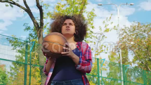 一个有非洲发型的年轻少女把一个篮球球扔进篮子里视频的预览图