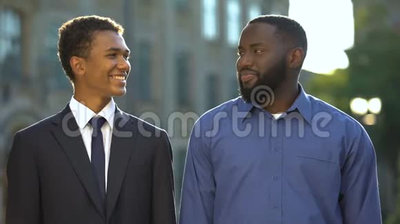 穿西装的男青少年和快乐的父亲在户外互相微笑学院视频的预览图
