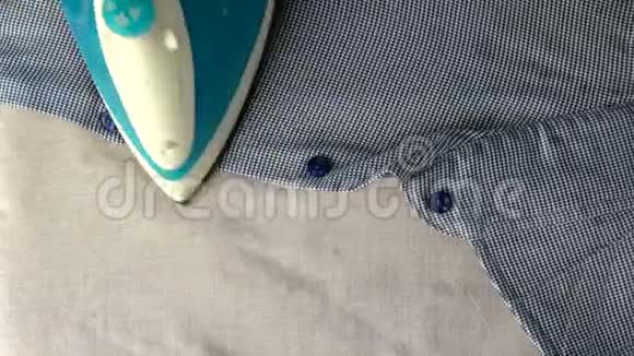 人手用电熨斗是熨烫蓝色衬衫上轻纺背景上景家庭工作概念特写镜头视频的预览图