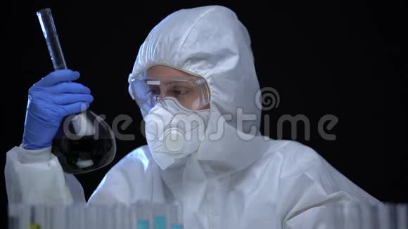 穿着防护服的女人在黑色背景下用深色液体研究瓶视频的预览图