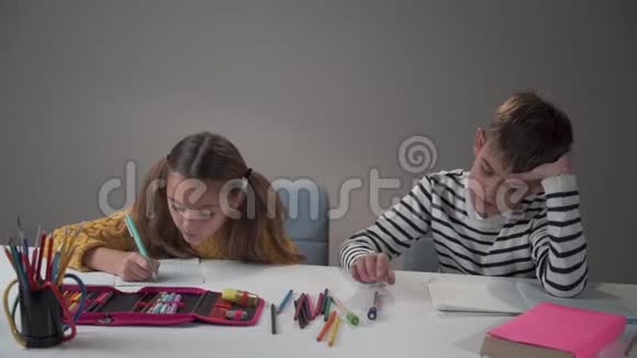 一个白人男孩在桌子上扔笔的肖像他那勤奋的女同学惊讶地看着他视频的预览图