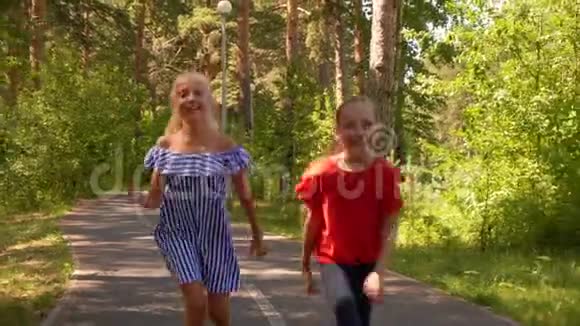 快乐少女少年在夏日公园的小路上奔跑微笑的女朋友在人行道上奔跑在镜头前跳跃视频的预览图