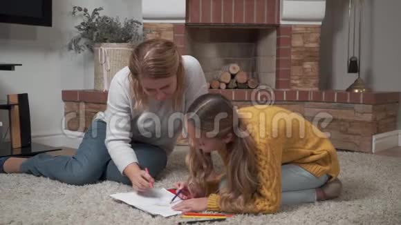 一位年轻的高加索母亲帮助她的女儿给这幅画上色的肖像成年女人和可爱的小女孩视频的预览图