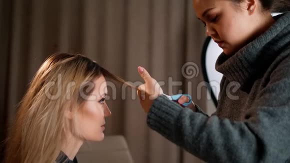 亚洲化妆师用剪刀剪头发在为庆祝圣诞节而装饰的室内视频的预览图