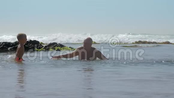 小男孩在海上慢动作把水溅到快乐的爸爸身上视频的预览图