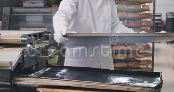 漂亮的成熟男人穿着白色的制服把货架上培育出来的原料装到烤箱里烤视频的预览图