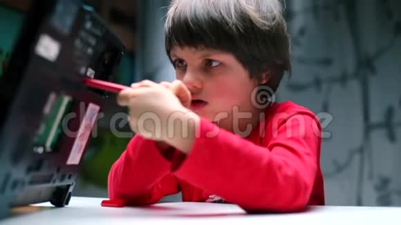一个穿红色衣服的男孩把一支钢笔插进笔记本电脑的背面视频的预览图