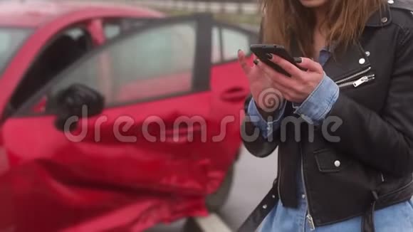 那个女孩站在路上一辆破车的背景上拿着一部电话视频的预览图