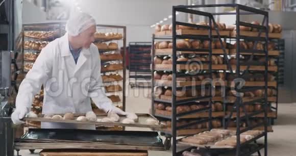 专业的面包师老头长得漂亮拿着装满生面包的大托盘装在架子上准备视频的预览图