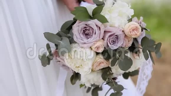 新娘穿着白色连衣裙捧着一束玫瑰特写镜头视频的预览图