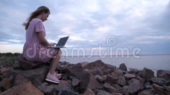 自由职业者在办公室外工作海边的女孩在用笔记本电脑工作4K慢慢视频的预览图